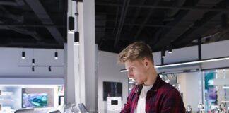 A young man chooses a laptop in an electronics store. A man looks at laptops in the computer department at the technology store. Buy a laptop