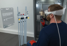 A man wearing an Apple Vision Pro next to a Siemens P5 power panel. He is looking at a digital overlay of BILT immersive instructions including a 3D rendering of the panel and a text window.